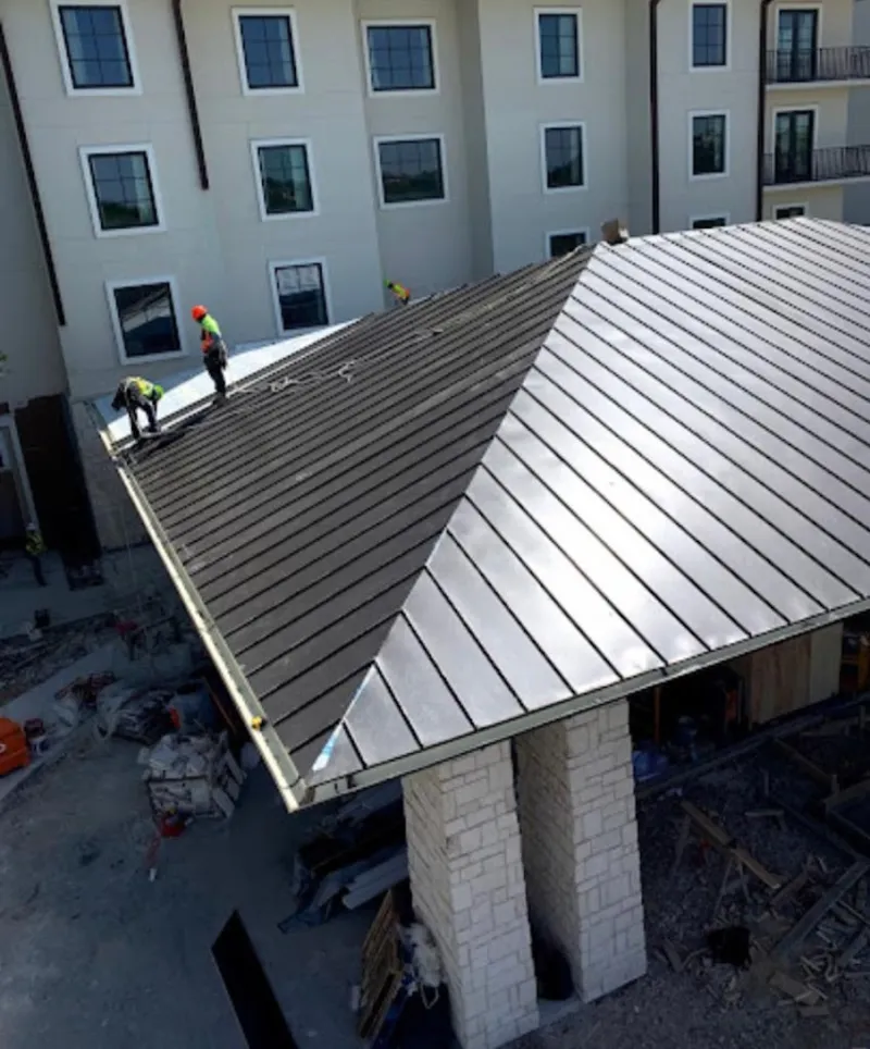 Crew installing standing seam metal roof panels on a commercial project in Cambria